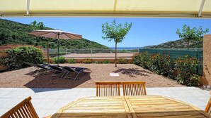An outdoor patio with a table and chairs, sun loungers, a pergola with a canopy, and a view of the sea and hills. - Tivella House - TIZZANO (TIZZANO)