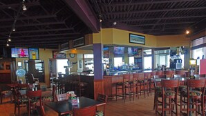 A restaurant with wooden tables and chairs, a bar area, and multiple televisions on the walls. - One Unit w/ Two Queen Beds | Breakfast Included | Direct Pool & Jacuzzi Access (Houghton Lake)