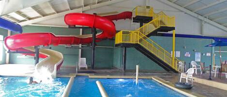 An indoor swimming pool with two slides, a yellow staircase, and a tire float.