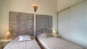 Een kamer met twee bedden, een wandlamp en een kledingkast.