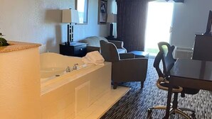 A hotel room with a bathtub, a desk, a chair, a TV, and a window. - Two Suites w/ King Bed & Lake View | Free Breakfast | Pool w/ Slide Access (Houghton Lake)