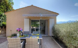 A small, single-story building with a covered patio, outdoor seating, and a view of the mountains. - A Casa Di Leandru - OCANA (OCANA)