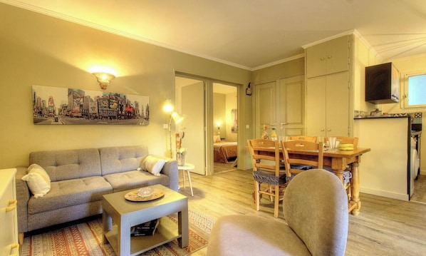 Ein Wohnzimmer mit Sofa, Couchtisch und Essbereich mit Stühlen und Tisch.