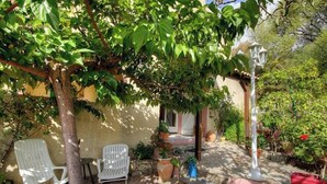 Un pati amb cadires blanques, una taula i plantes en testos.