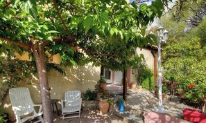 Eine Terrasse mit weißen Stühlen, einem Tisch und Topfpflanzen.