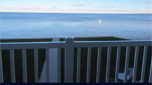 Vista da un balcone su un'acqua calma, con ringhiera bianca e una sedia in primo piano.