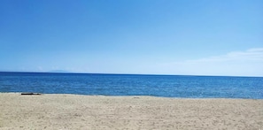 Ein Strand mit blauem Himmel und ruhiger See.