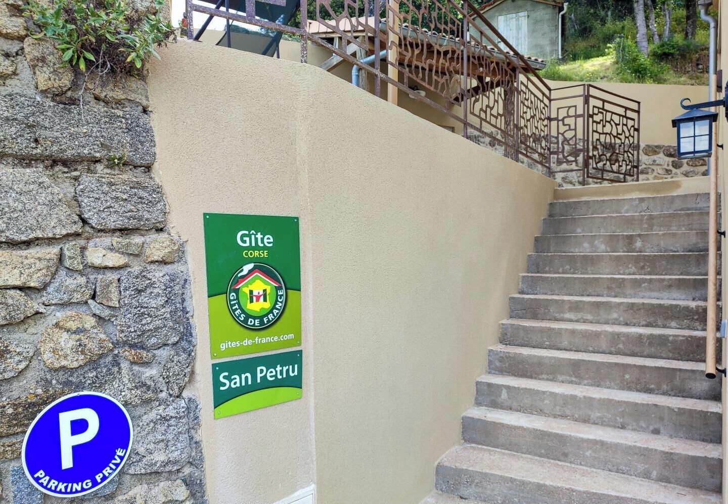 A staircase leading to a building with a green sign indicating 'Gîte Corse' and 'San Petru'.
