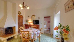 A dining area with a table, chairs, a television, and a fireplace. - Le 51364 - AREGNO - Gîte (AREGNO)