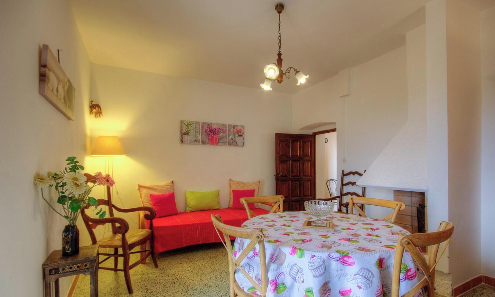 A cozy room with a bed, a dining table, chairs, a lamp, and a painting on the wall.