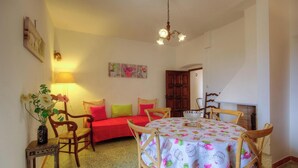 A cozy room with a bed, a dining table, chairs, a lamp, and a painting on the wall. - Le 51364 - AREGNO - Gîte (AREGNO)