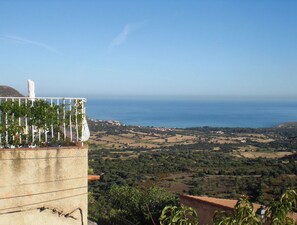 A coastal view with a building featuring a balcony with plants and a white object on it. - Le 51364 - AREGNO - Gîte (AREGNO)