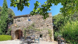 A stone building with a wooden door, outdoor seating, and a garden. - Domaine Vecchio 2 - CHIATRA DI VERDE (CHIATRA DI VERDE)