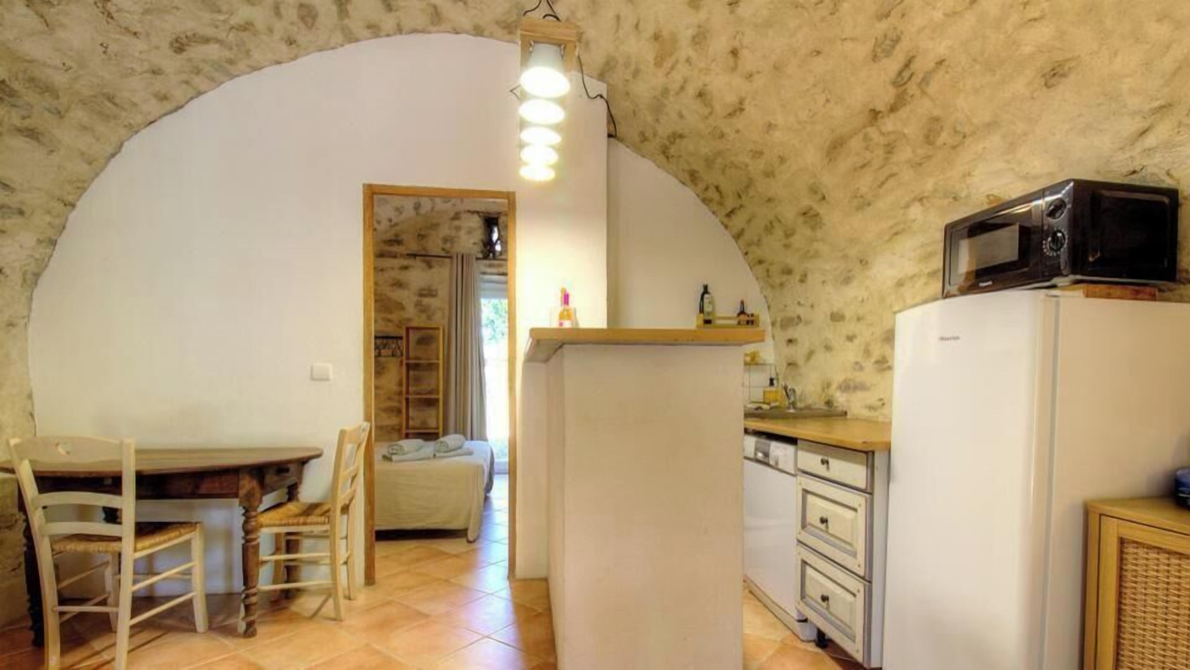 A compact kitchen with a microwave, refrigerator, and wooden dining table with chairs.