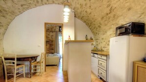 A compact kitchen with a microwave, refrigerator, and wooden dining table with chairs. - Domaine Vecchio 2 - CHIATRA DI VERDE (CHIATRA DI VERDE)