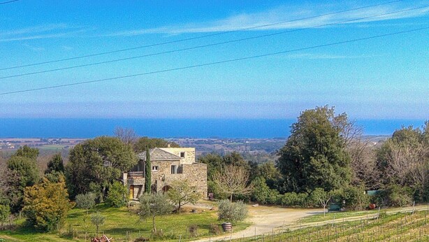 A stone building with a sloped roof, surrounded by trees and a clear view of the sea. - Domaine Vecchio 2 - CHIATRA DI VERDE (CHIATRA DI VERDE)