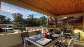 An outdoor patio with a table set for dining, surrounded by chairs, and a wooden ceiling. - Du soleil - PORTO VECCHIO (PORTO VECCHIO)