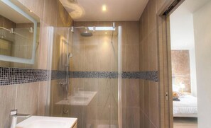Ein modernes Badezimmer mit einer begehbaren Glasdusche, einem Waschbecken und einem Spiegel.