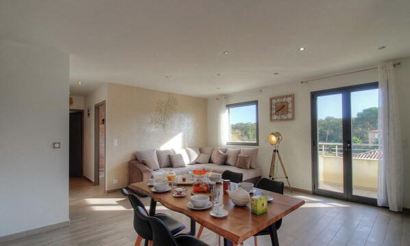 Ein Essbereich mit einem für das Frühstück gedeckten Tisch, einer Couch und einem Balkon mit Blick.