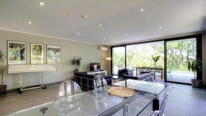 A modern room with a glass table, a flat-screen TV, a sofa, and a balcony with plants. - Casa Vittoria - FELICETO (FELICETO)
