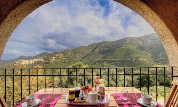 Ein Tisch mit Frühstücksangebot und Blick auf eine Berglandschaft.