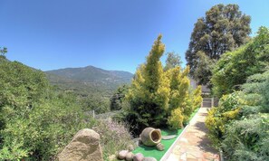 Ein Garten mit einem Pfad, einem großen Felsen und Blick auf die Berge.