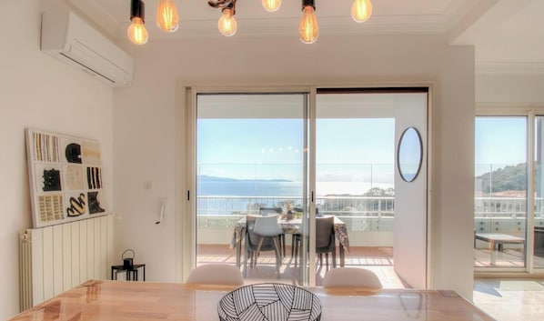 Ein modernes Zimmer mit einer großen Schiebeglasdoor, die auf einen Balkon mit Blick auf die Stadt führt.