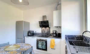Eine kleine Küche mit Kühlschrank, Herd, Backofen und Spüle.