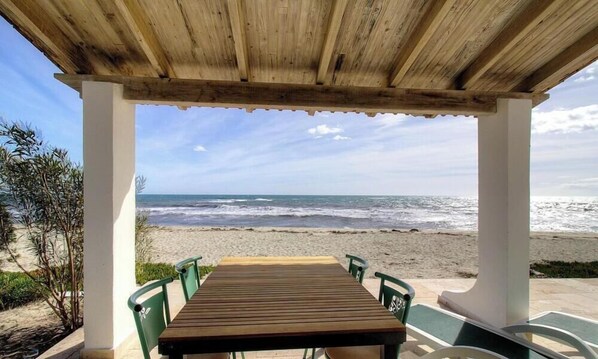 A wooden table and chairs under a wooden pergola with a view of the beach and ocean. - Quenza, N°18 - GHISONACCIA (GHISONACCIA)