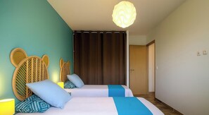 Ein Hotelzimmer mit zwei Betten, einem Holzkopfstück, einem Vorhang, einer Tür und einer Leuchte.