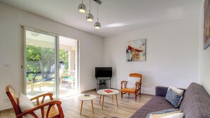 A living room with a sofa, a chair, a small table, a television, and a painting on the wall. - Villa E Lecce - SANTA LUCIA DI MORIANI (SANTA LUCIA DI MORIANI)