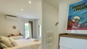 Una camera da letto con un letto, un comodino, una finestra e un poster appeso al muro.