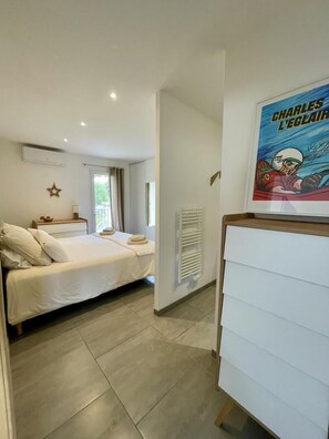 Ein Schlafzimmer mit einem Bett, einem Nachttisch, einem Fenster und einem Poster an der Wand.