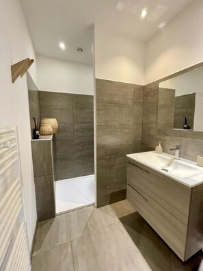 Ein modernes Badezimmer mit Badewanne, Waschtisch mit Spiegel und Duschbereich.