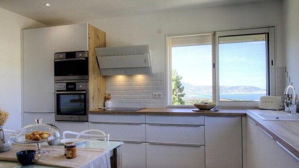 Una cucina moderna con elettrodomestici integrati, una finestra vista panoramica e un'area pranzo con tavolo imbandito per due persone.
