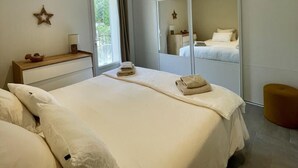 Una camera da letto con un letto grande, un comodino, uno specchio e una finestra con tende.