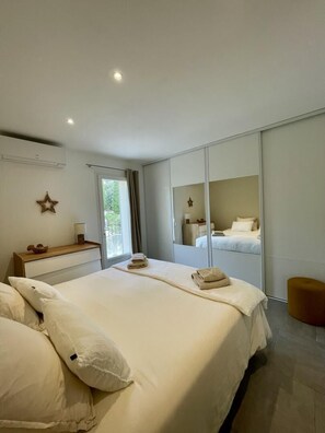 Ein Schlafzimmer mit einem großen Bett, einem Nachttisch, einem Spiegel und einem Fenster mit Vorhängen.