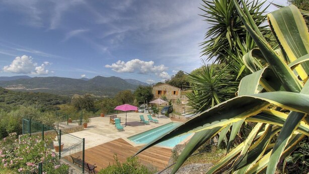 Ein Pool mit Liegestühlen, eine Terrasse und Blick auf Berge.