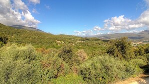 Eine gebirgige Landschaft mit vereinzelten Gebäuden und blauem Himmel.