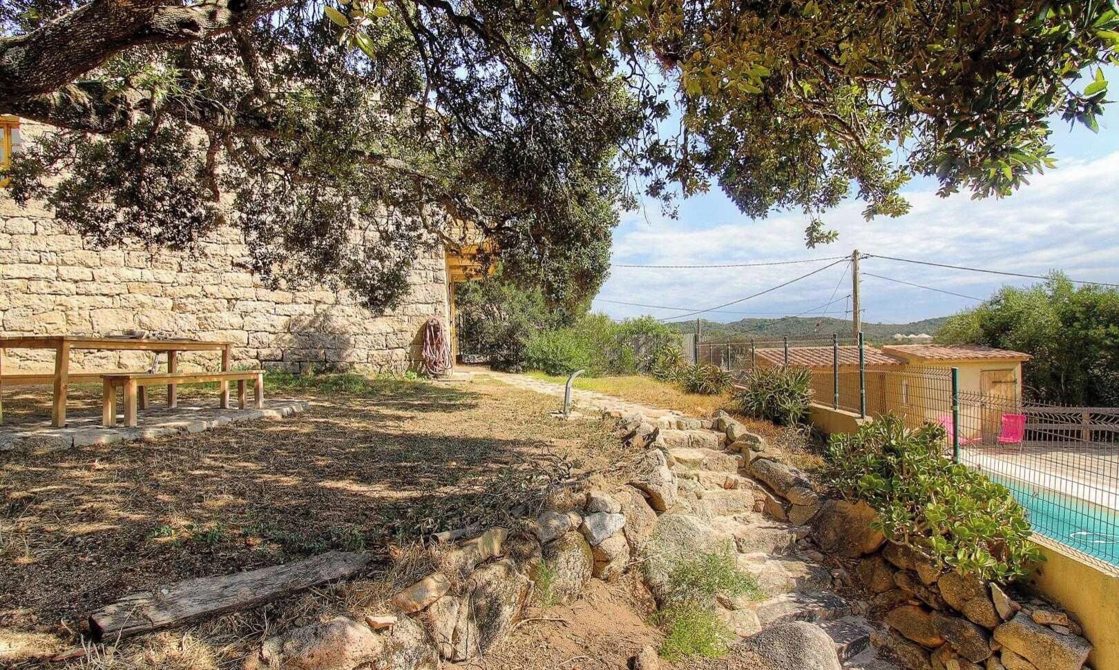 A stone building with a bench, a pool, and a fenced area.