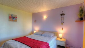 A bedroom with a bed, two bedside lamps, a wall-mounted light fixture, a hanging plant, and a painting. - Domaine des yuccas - CALCATOGGIO (CALCATOGGIO)