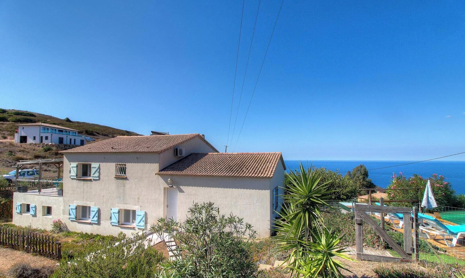 A two-story building with a tiled roof, a balcony, and a view of the sea.