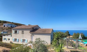 Ein zweistöckiges Gebäude mit Ziegeldach, einem Balkon und Blick auf das Meer.