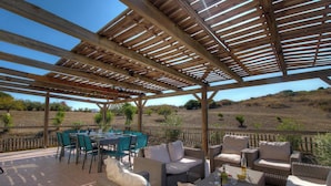 An outdoor patio with wooden pergola, green chairs, wicker sofas, and a table set for dining. - Domaine des yuccas - CALCATOGGIO (CALCATOGGIO)