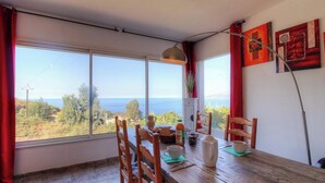 A dining area with a table set for two, a view of the sea, and a large window. - Domaine des yuccas - CALCATOGGIO (CALCATOGGIO)