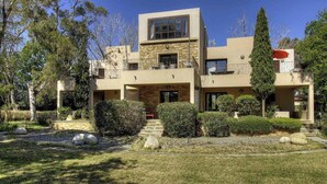 A modern two-story house with a stone facade, a balcony, and a well-maintained garden with rocks and shrubs. - Résidence U Quarciu - GHISONACCIA (GHISONACCIA)