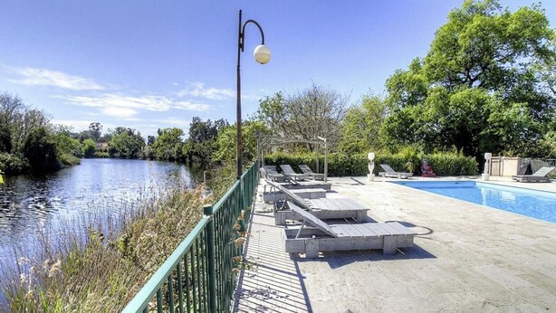 A pool area with lounge chairs, a bridge, and a lamp post. - Résidence U Quarciu - GHISONACCIA (GHISONACCIA)