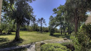 A park with trees, a grassy area, and a stone path. - Résidence U Quarciu - GHISONACCIA (GHISONACCIA)