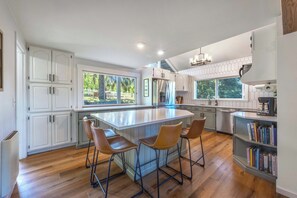 Uma cozinha moderna com ilha central, banquetas e estante.