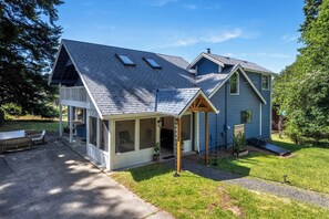 Uma casa de dois andares com varanda coberta, garagem e um pequeno terraço.